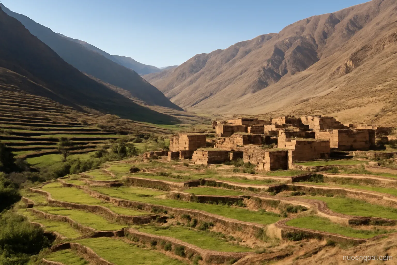 A high dry mountain valley with terraced fields and a mud-brick village under sharp clear light