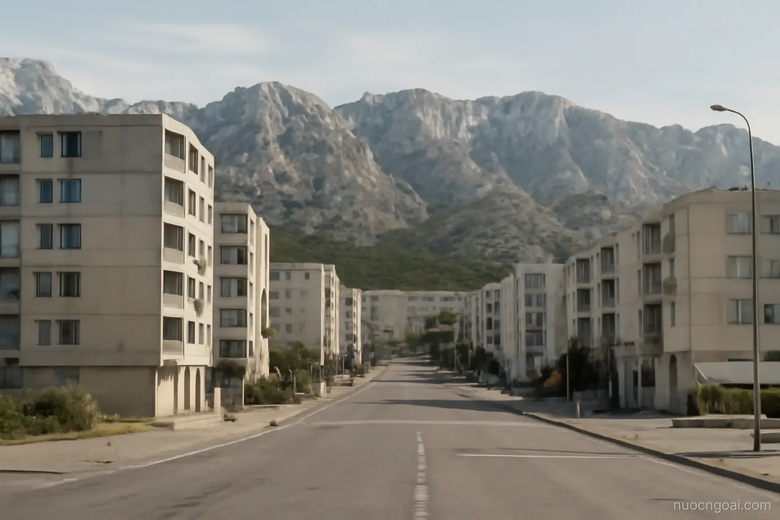 A coastal town of concrete apartment blocks below bare limestone ridges, empty streets in low season