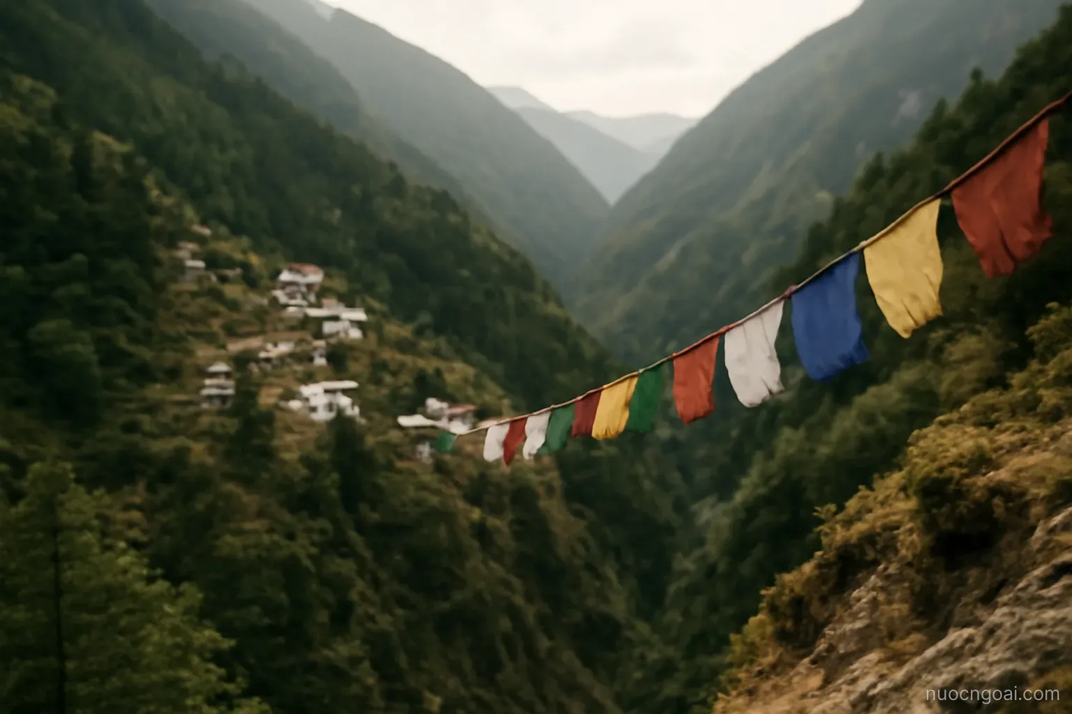Steep forested valleys with white-walled buildings on the slopes, prayer flags on a ridge in thin air