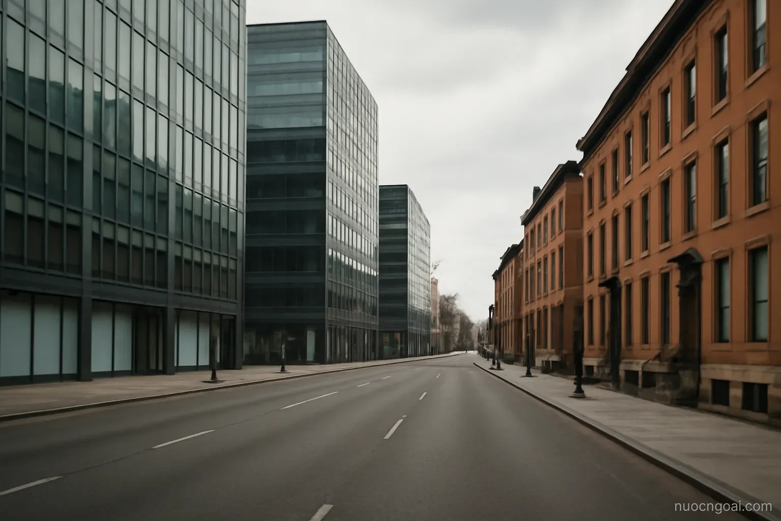 Glass office towers and brick townhouses facing each other across a wide boulevard on an overcast afternoon