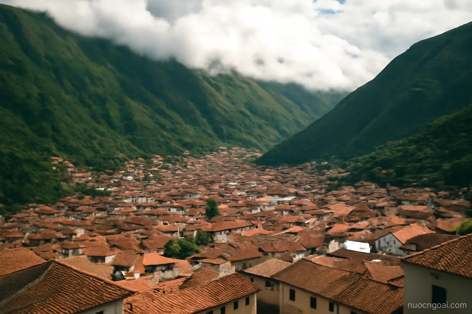 A high valley city packed between green volcanic slopes, tiled roofs and cloud spilling over the ridge