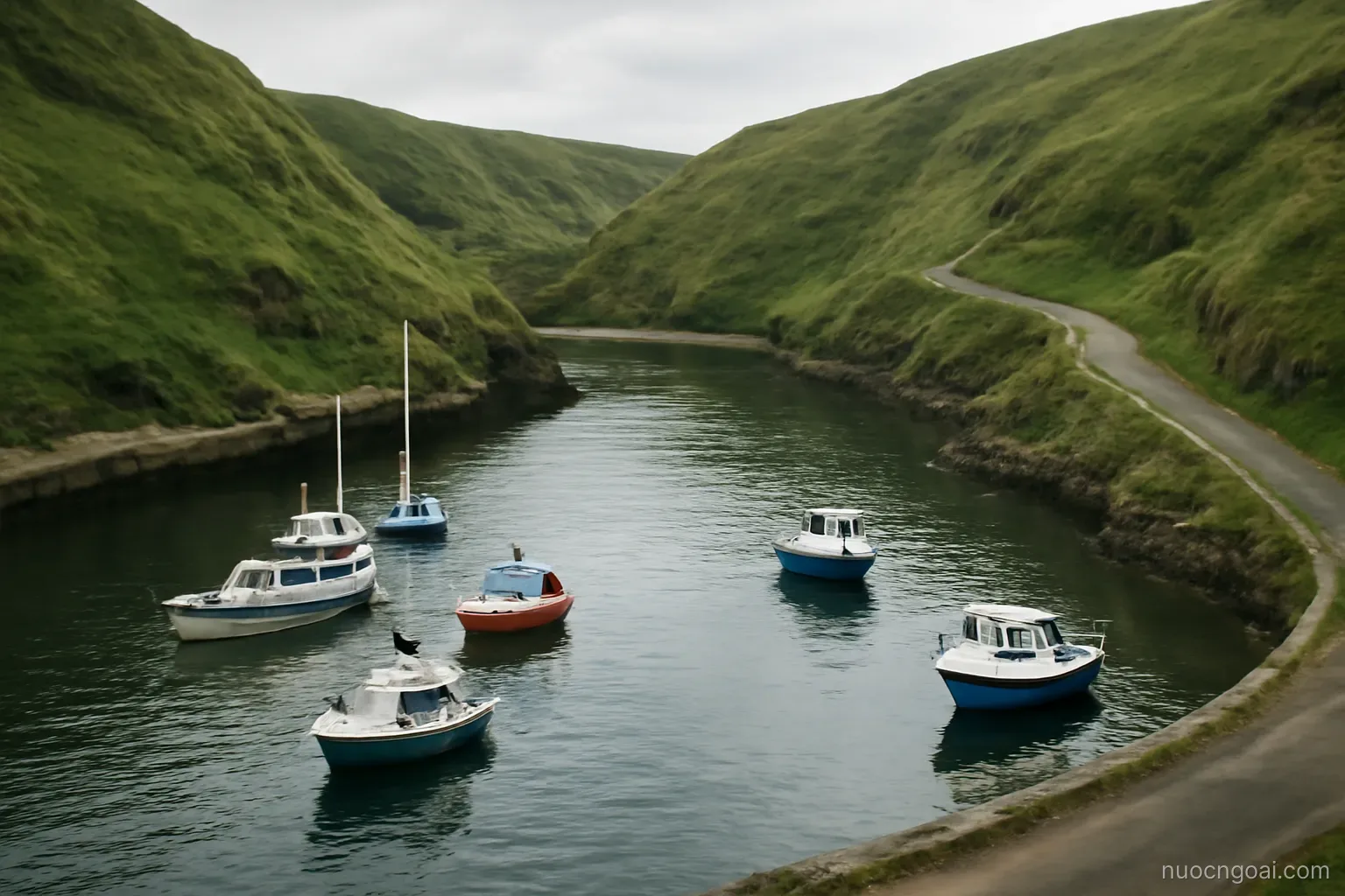 A small deep horseshoe harbour ringed by steep green hills, moored boats and a narrow road climbing above the water