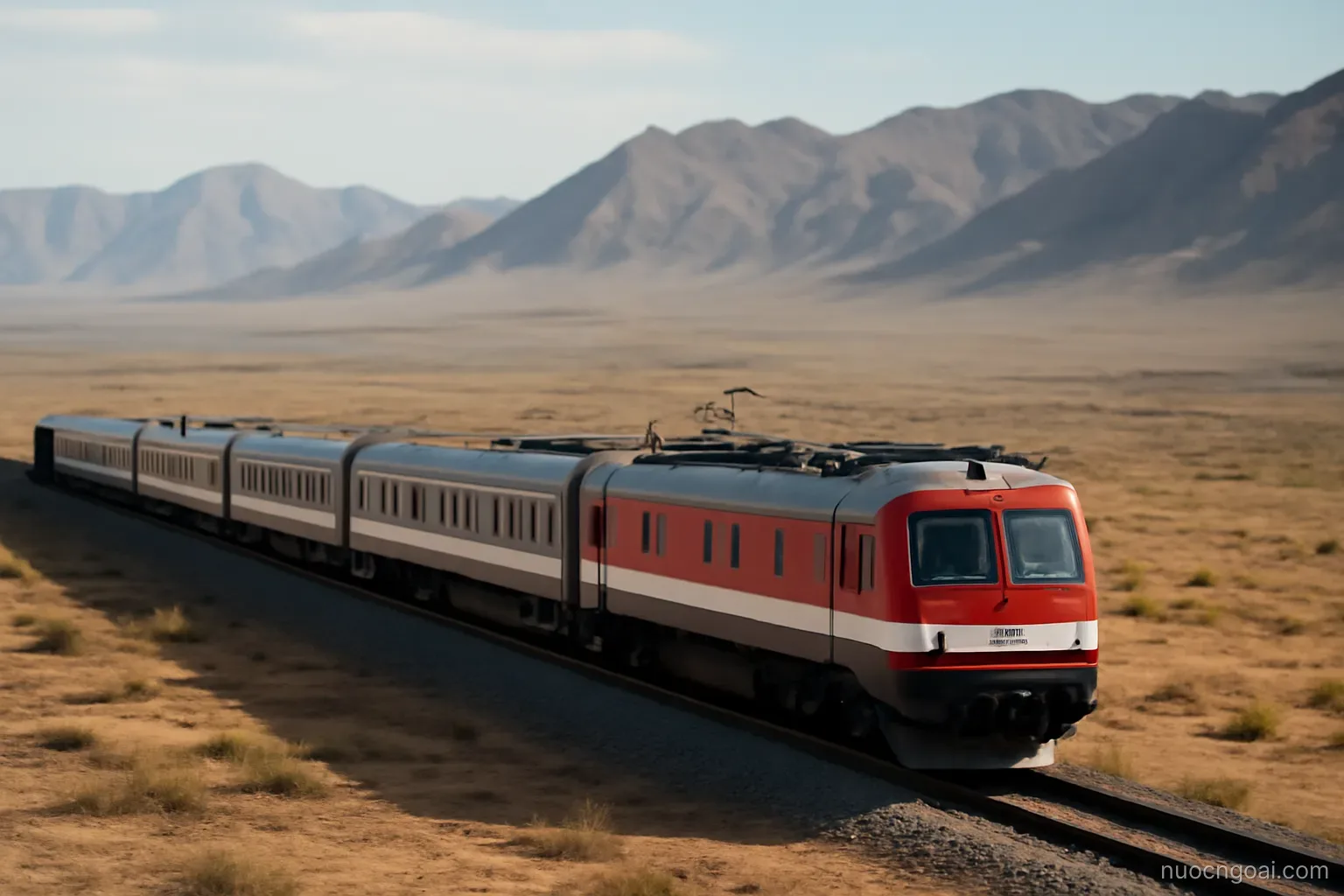 A long-distance train crossing an arid plateau with bare mountain ridges lining the far horizon