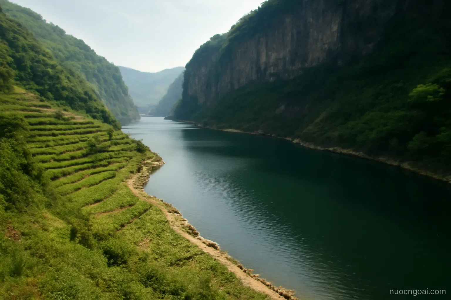 A long narrow freshwater lake edged by steep escarpment with small terraced fields running down to the shore