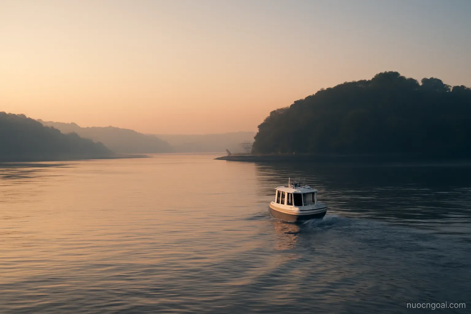 A wide estuary at dawn with a small passenger boat crossing towards a forested peninsula of low hills