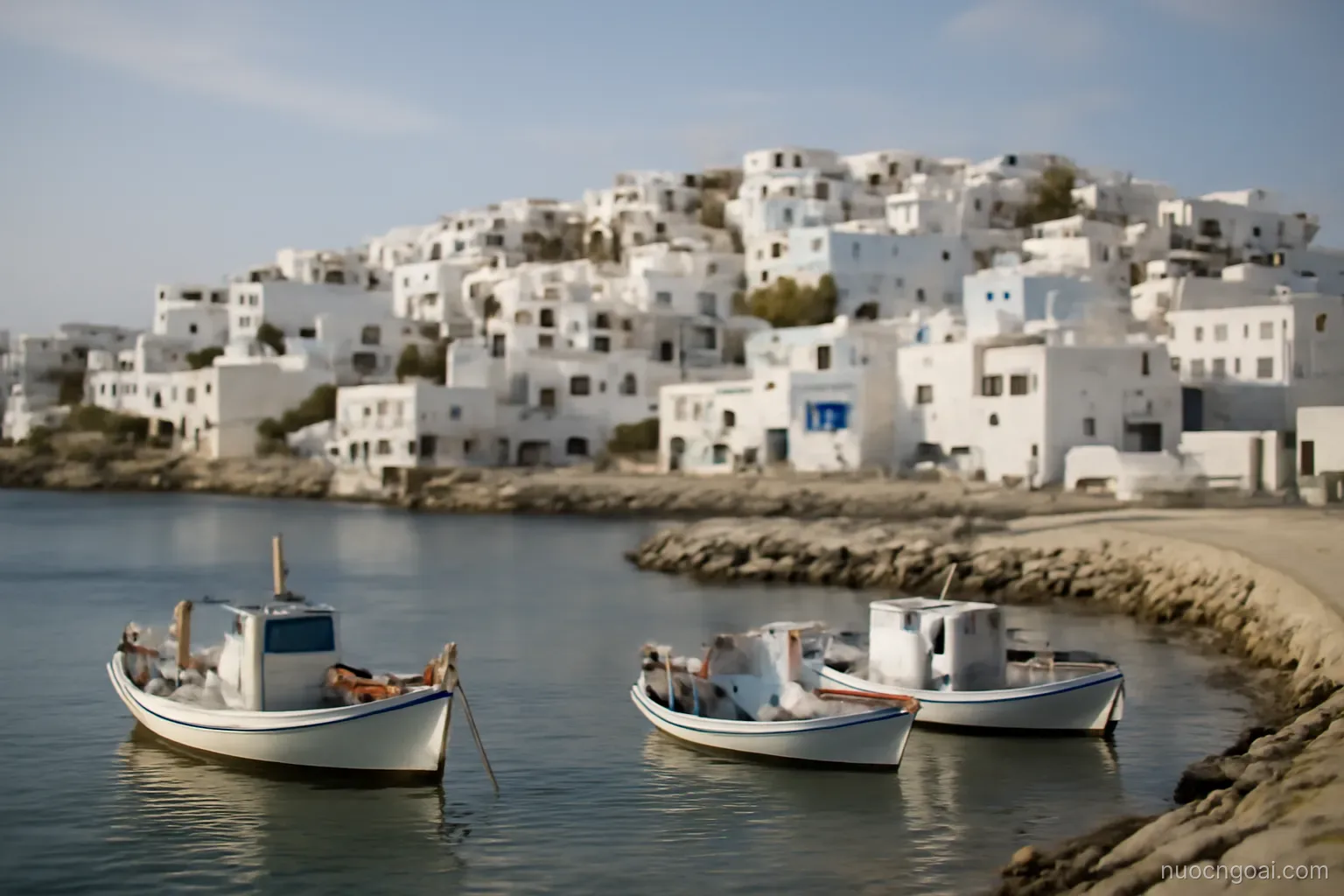 A whitewashed coastal town of low cubic houses above a small harbour with fishing boats and a stone breakwater